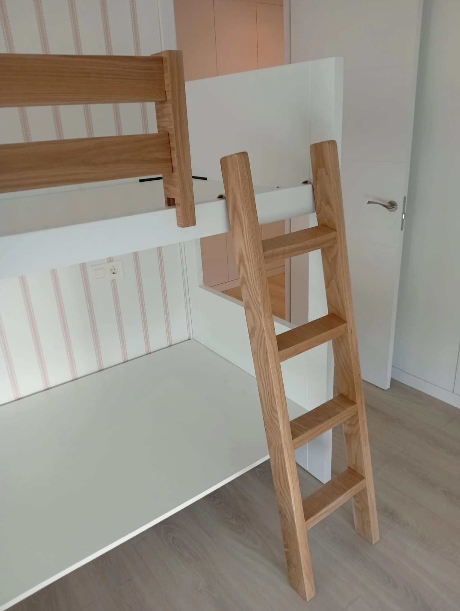 Fotografía original de la escalera de madera y la estructura blanca de las camas