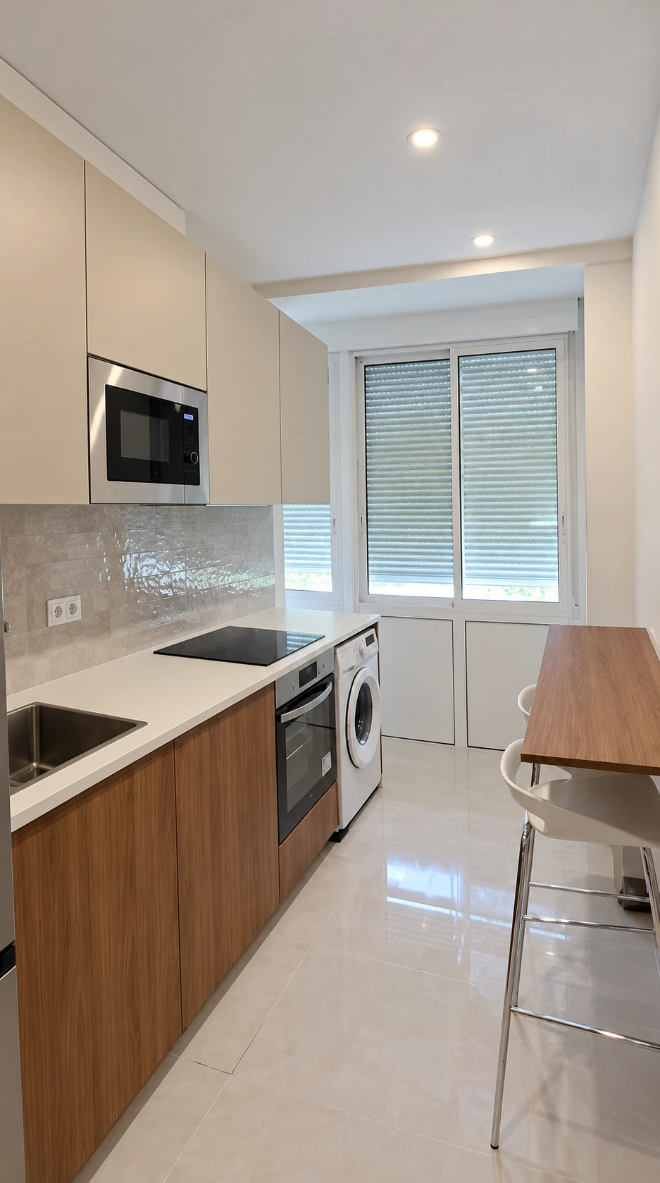 Cocina reformada con muebles de madera, frentes claros, horno, lavadora y barra