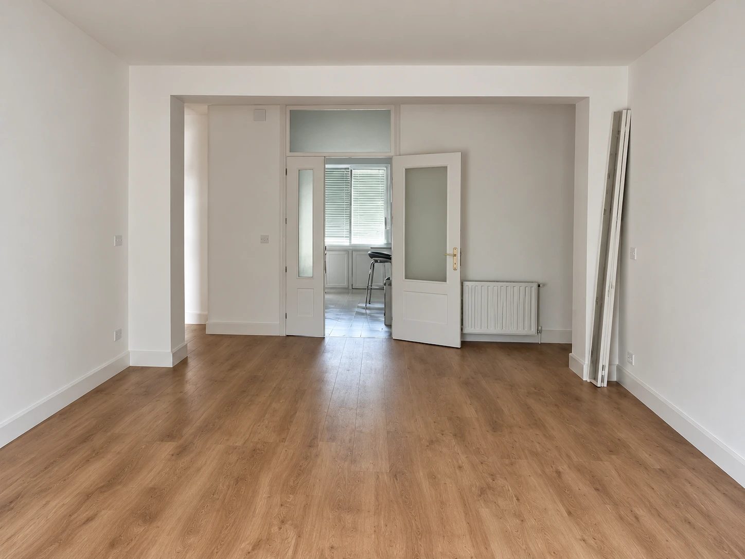 Salón de la vivienda reformada para alquilar, con suelo de madera y paredes lisas